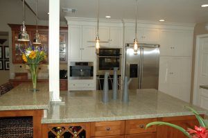 Modern kitchen with white cabinets, stainless steel appliances, and a granite island centerpiece