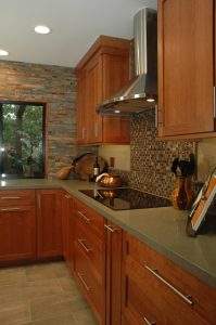 Modern kitchen with wood cabinets, stone backsplash, and stainless steel range hood