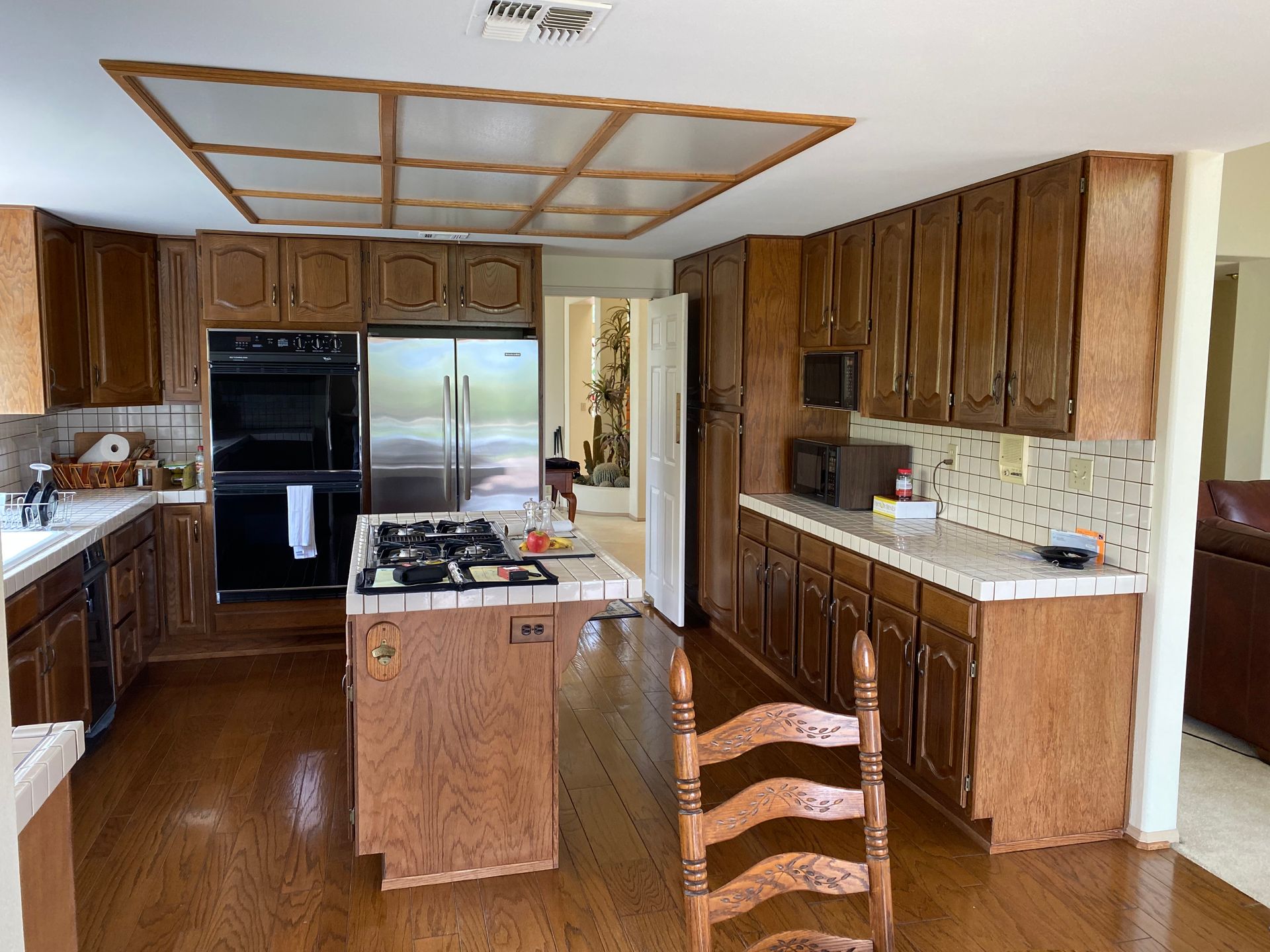 Wood-paneled kitchen with central island, black appliances, and a glass door at the back