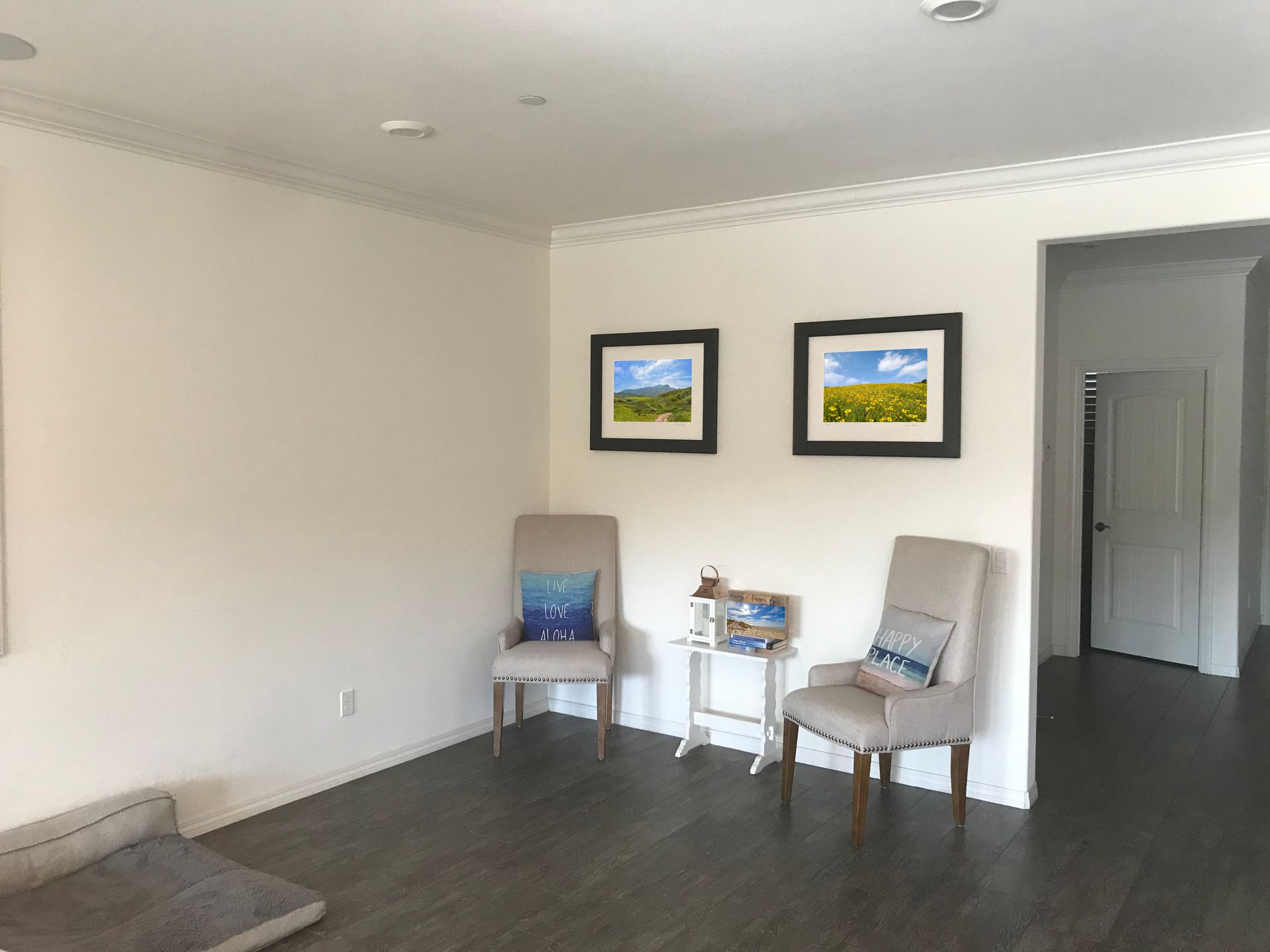 Minimal living room with two chairs, small table, and framed wall art.