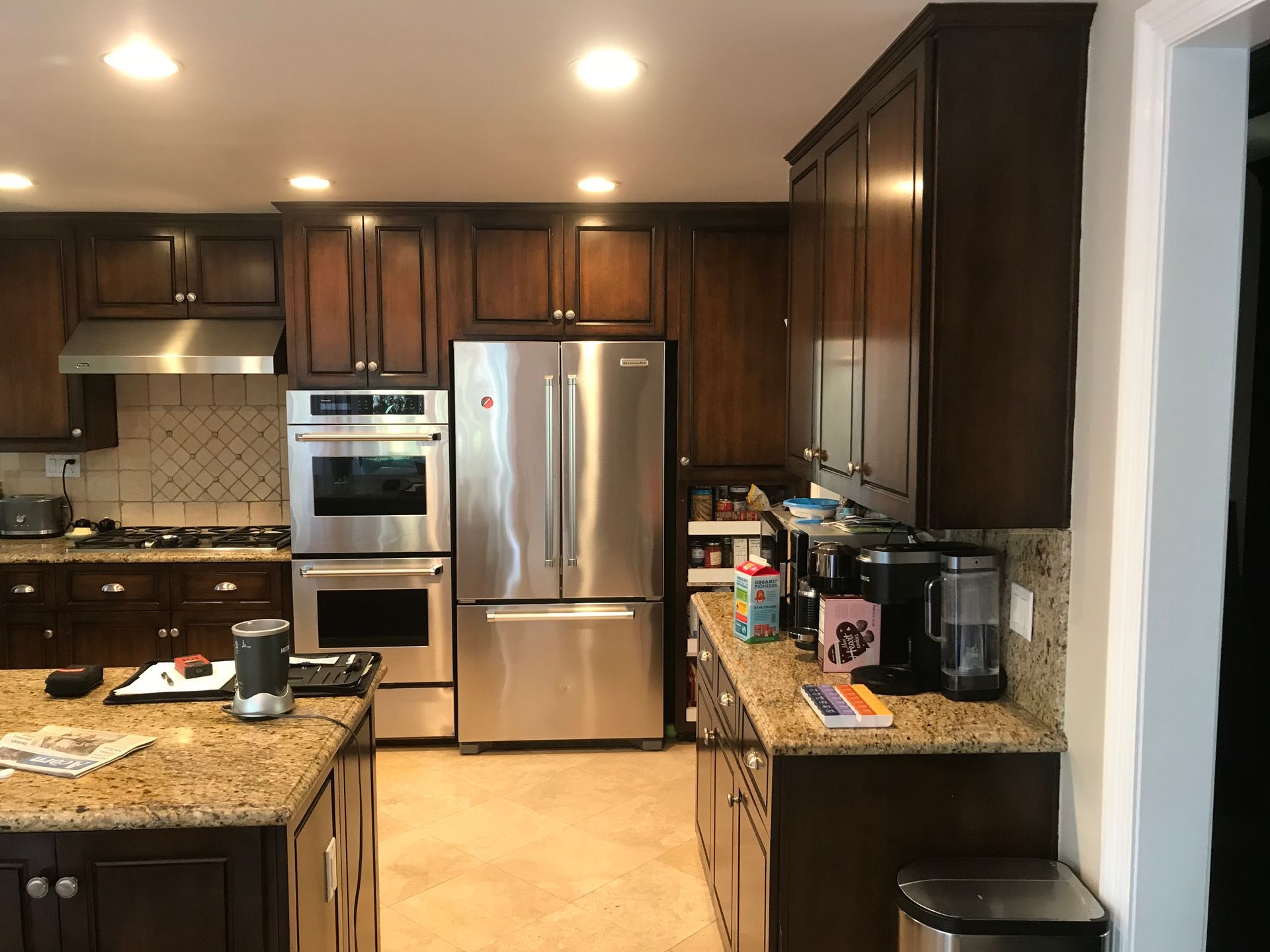 Modern kitchen with dark wood cabinets, granite counters, stainless steel appliances, and a central island.