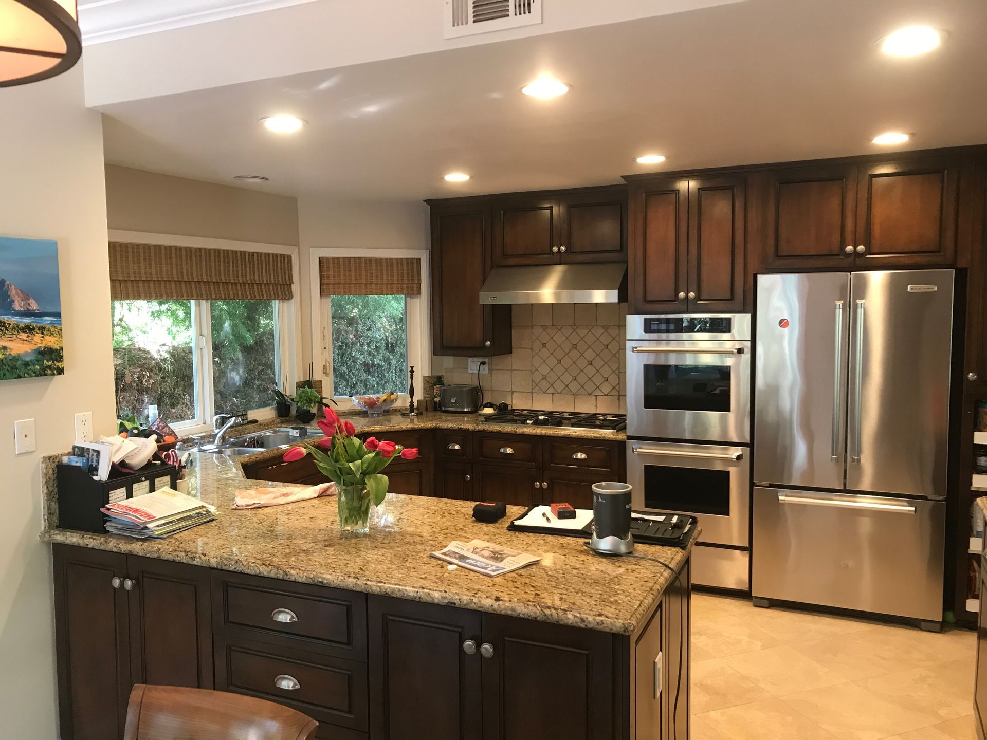Modern kitchen with dark wood cabinets, granite island, stainless steel appliances, and recessed lighting.