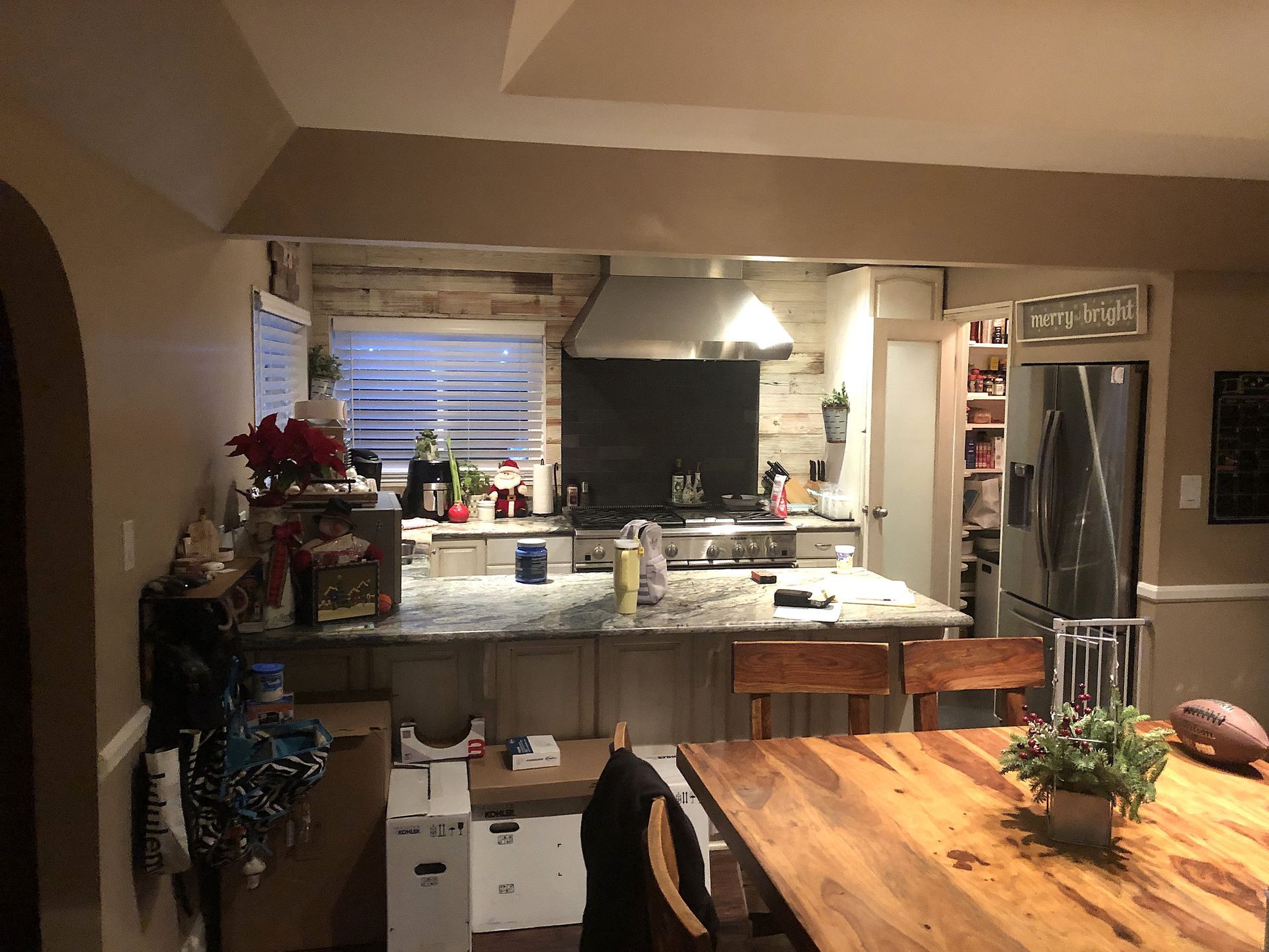 Kitchen with granite island, sink under window, and stainless steel refrigerator in a warm-toned home interior.