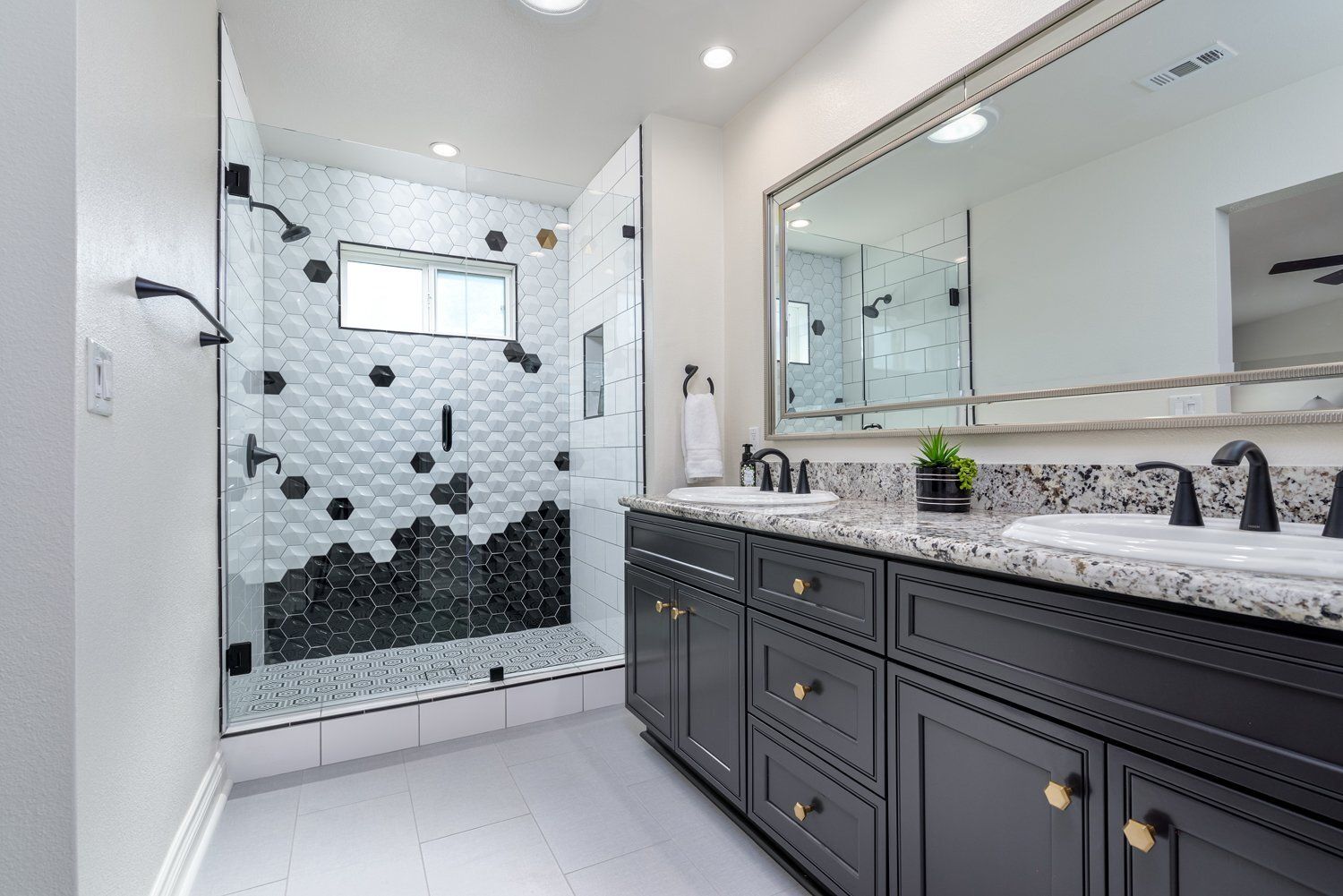 Modern bathroom with glass shower, black vanity, and large mirror