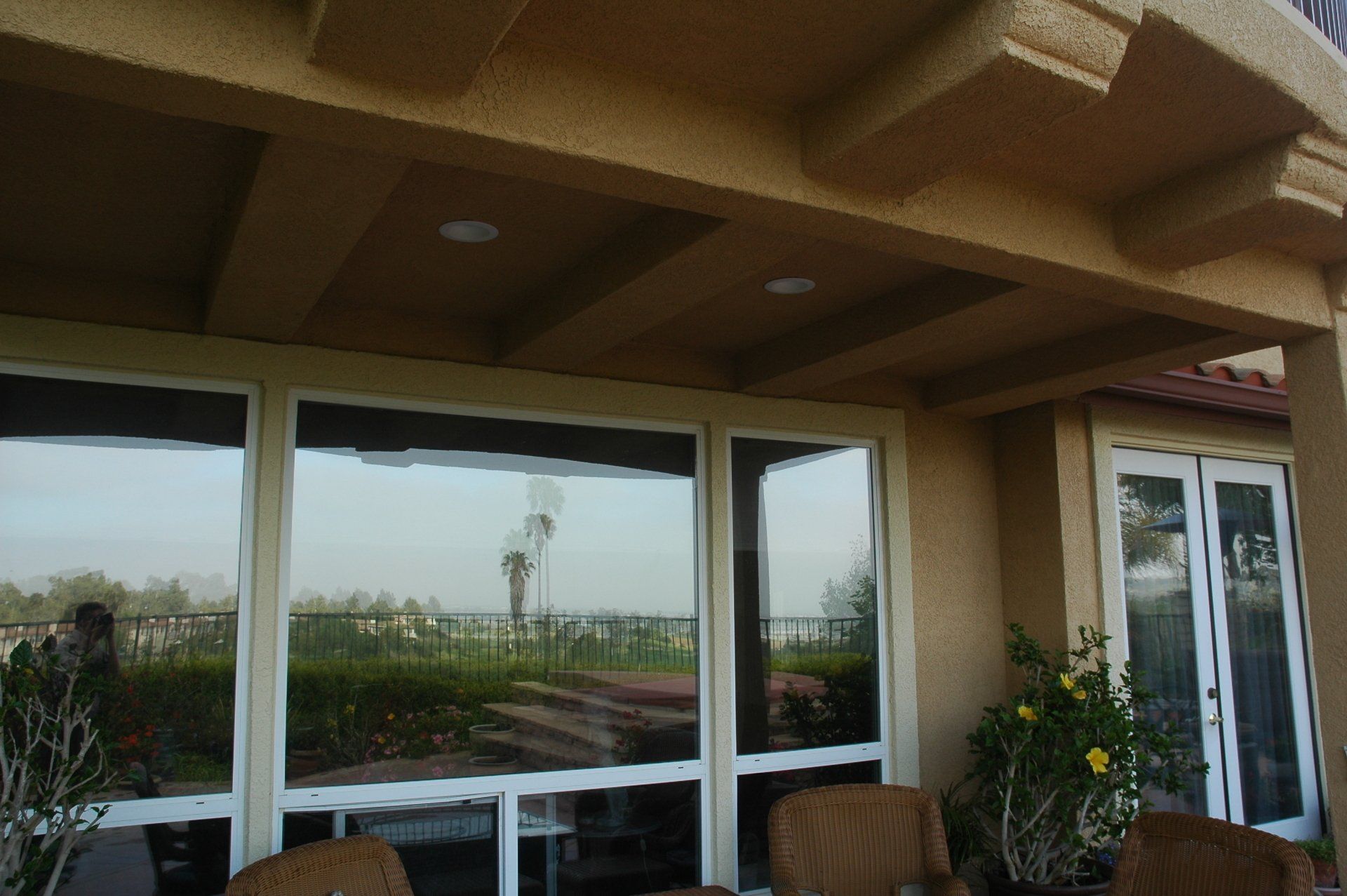Patio with beige ceiling and glass windows overlooking a green landscape and cloudy sky