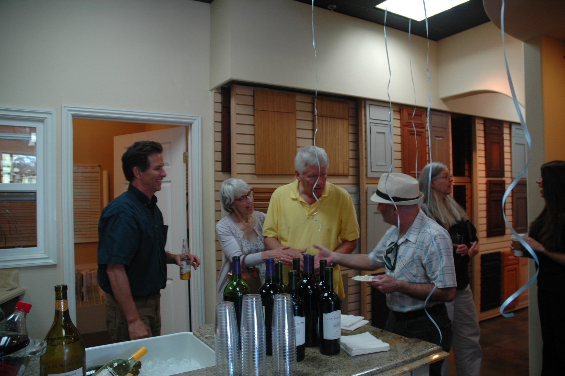 People gathered around a counter with bottles and cups at an indoor event