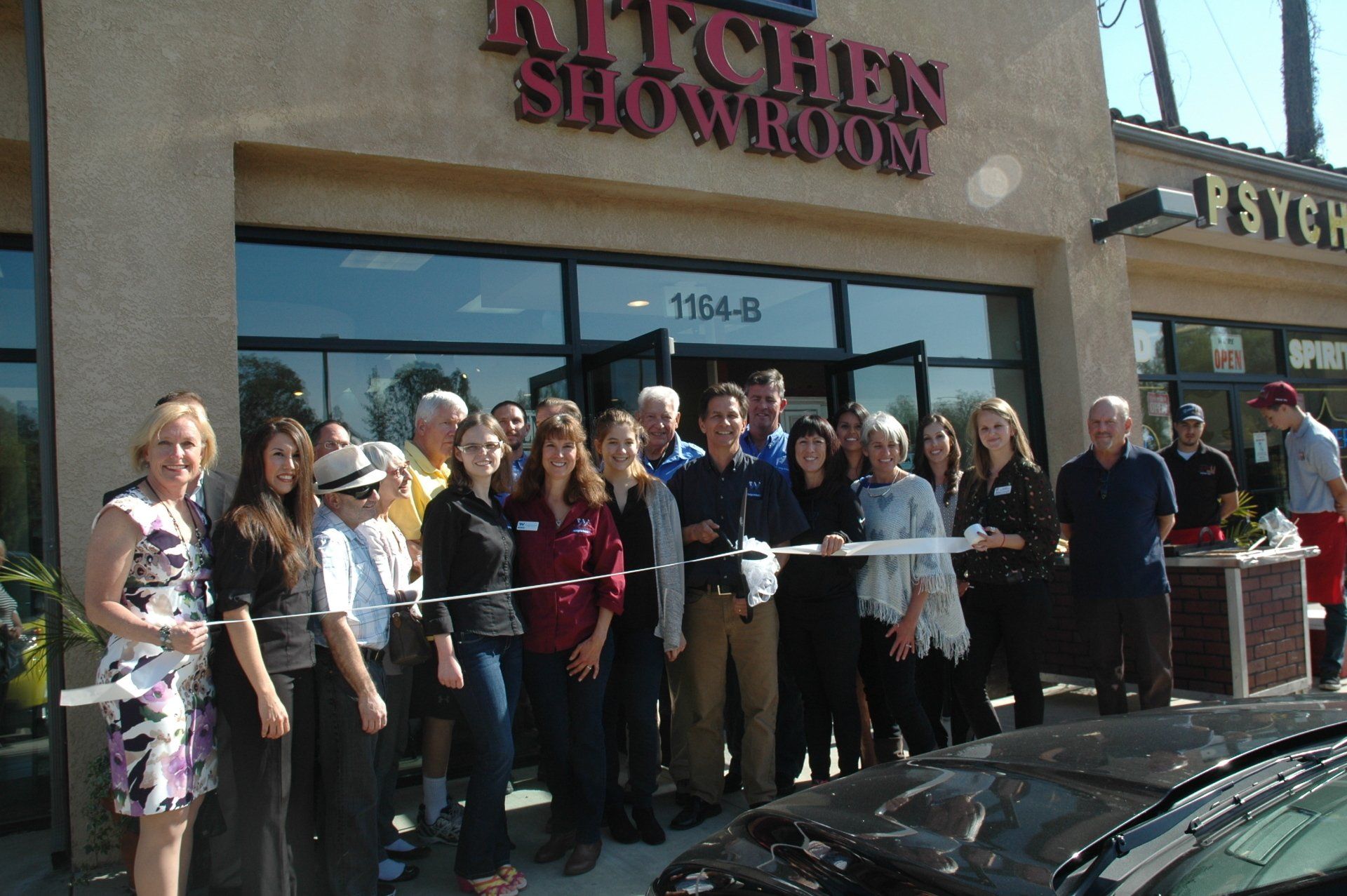 Group posing with a ribbon at the grand opening of Kitchen Showroom storefront