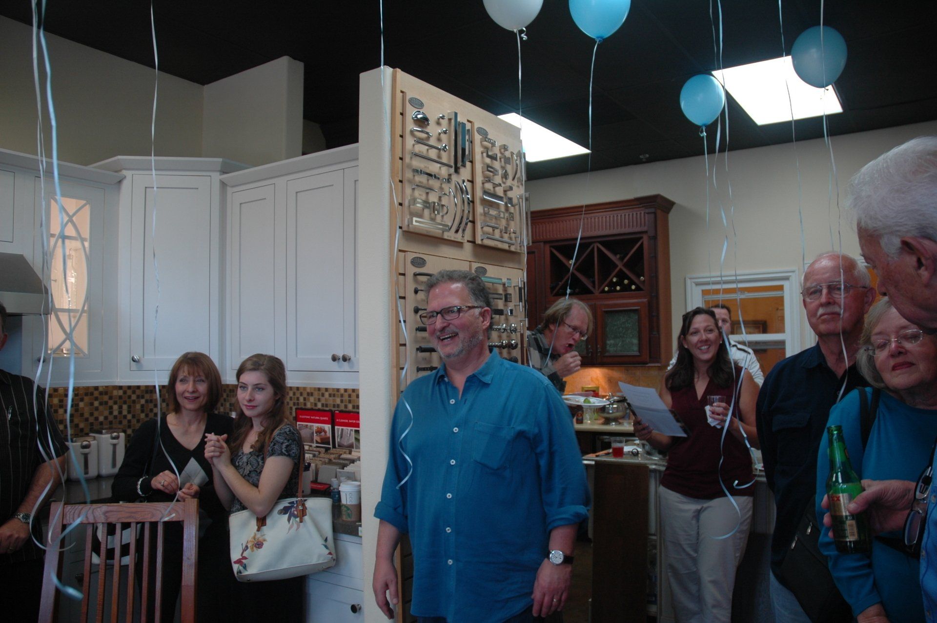 People gathered in a decorated room with balloons, chatting and holding drinks at a social event.