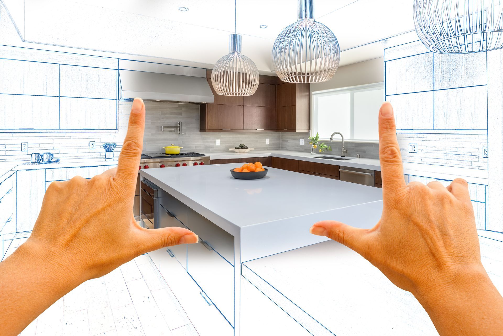 Hands framing a modern white kitchen with an island and hanging pendant lights.