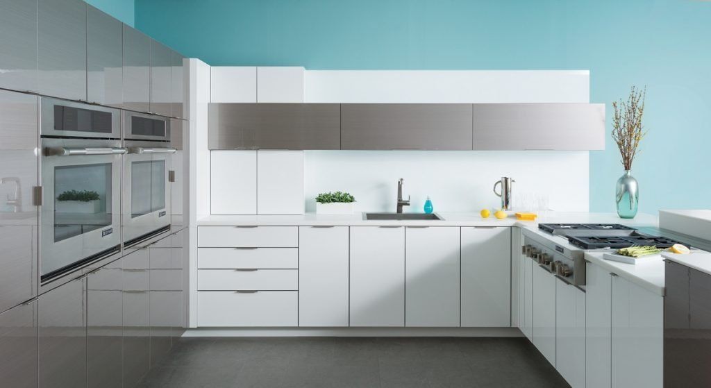 Modern white kitchen with stainless steel appliances, long counters, and blue accent wall