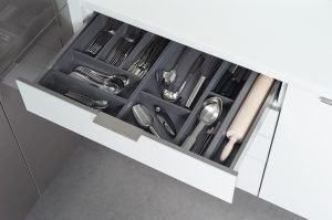Open kitchen drawer with organized cutlery and utensils in gray compartments