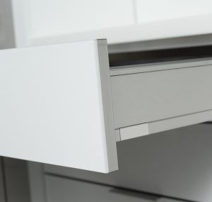 White cabinet drawer partially open, showing a sleek modern handle and gray interior.