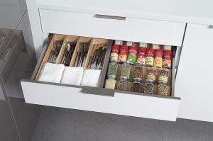 Open kitchen drawer with organized compartments for utensils and spice jars