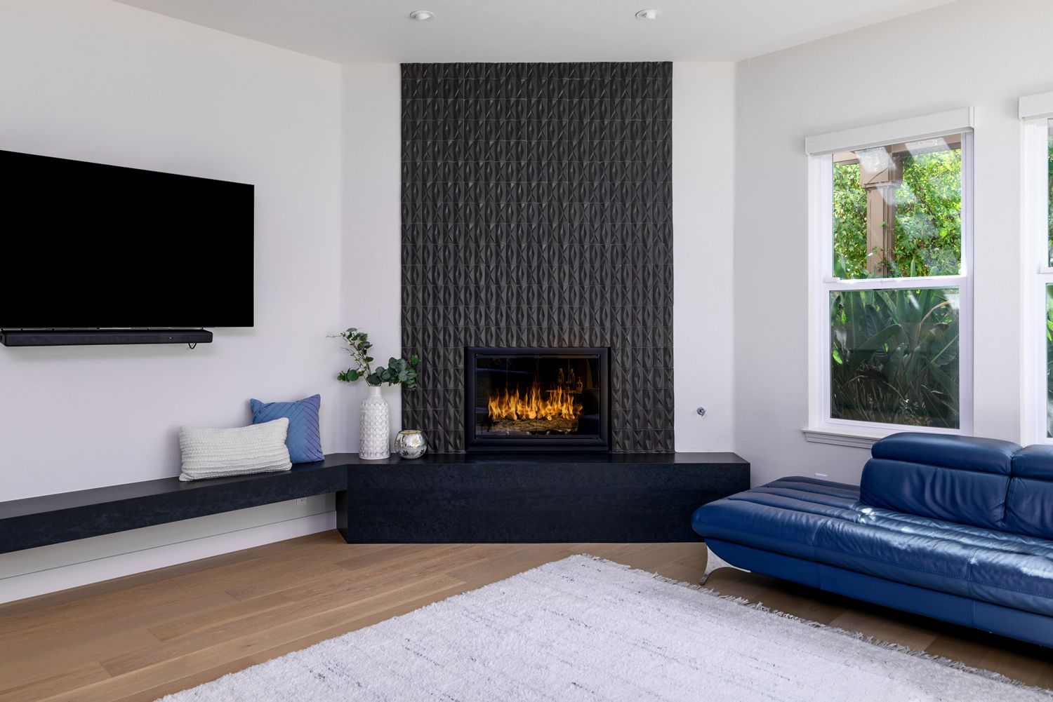 image shows a fireplace with charcoal gray raised, ribbed, tile, a black hearth, in a family room, Thousand Oaks, CA home remodel