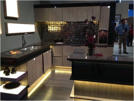 Modern kitchen with dark cabinets, under-cabinet lighting, island, and two people in the background