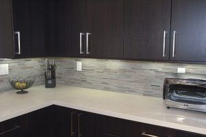 Modern kitchen corner with dark cabinets, light countertop, mosaic backsplash, and a toaster oven