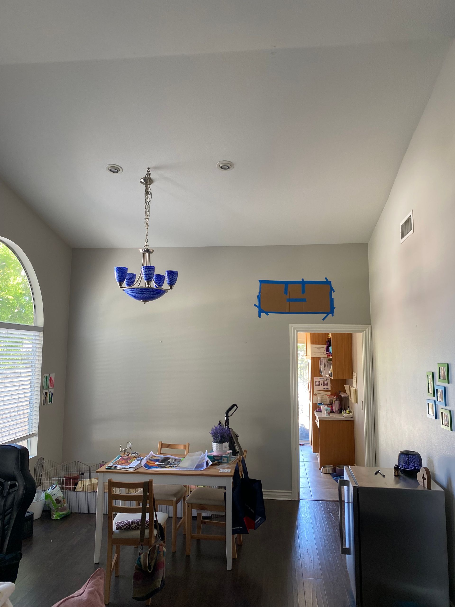 Dining room with a blue chandelier, table set for a meal, and an open doorway to another room.