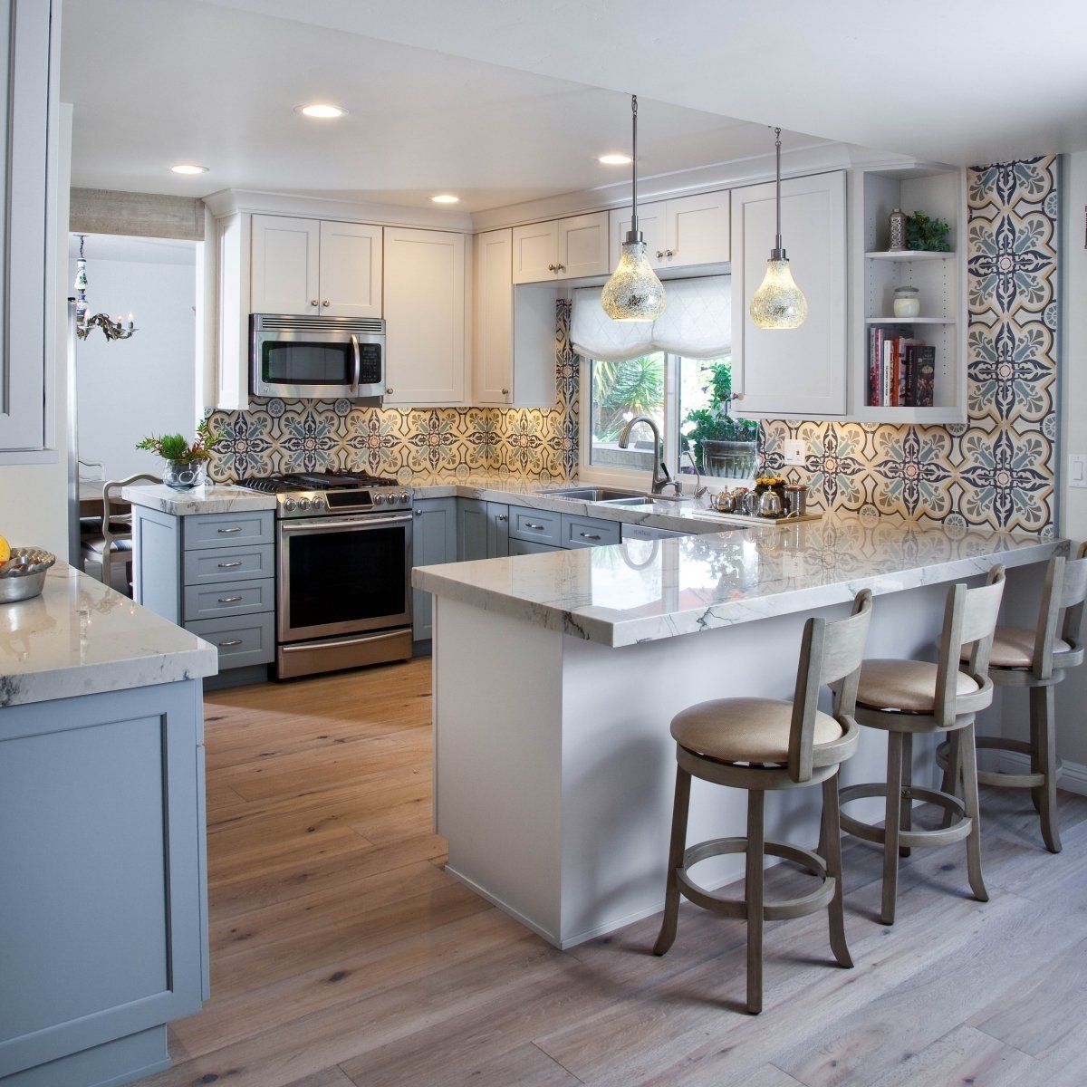 Bright modern kitchen with white cabinets, mosaic backsplash, island, and three stools under pendant lights