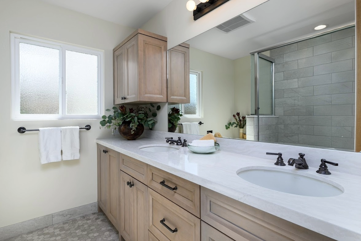 Modern bathroom vanity with double sinks, wood cabinets, mirror, and tiled walk-in shower