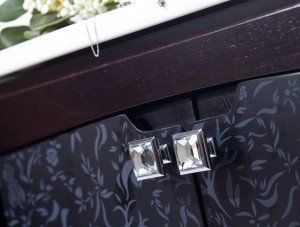Decorative black cabinet with mirrored square handles and floral pattern detail