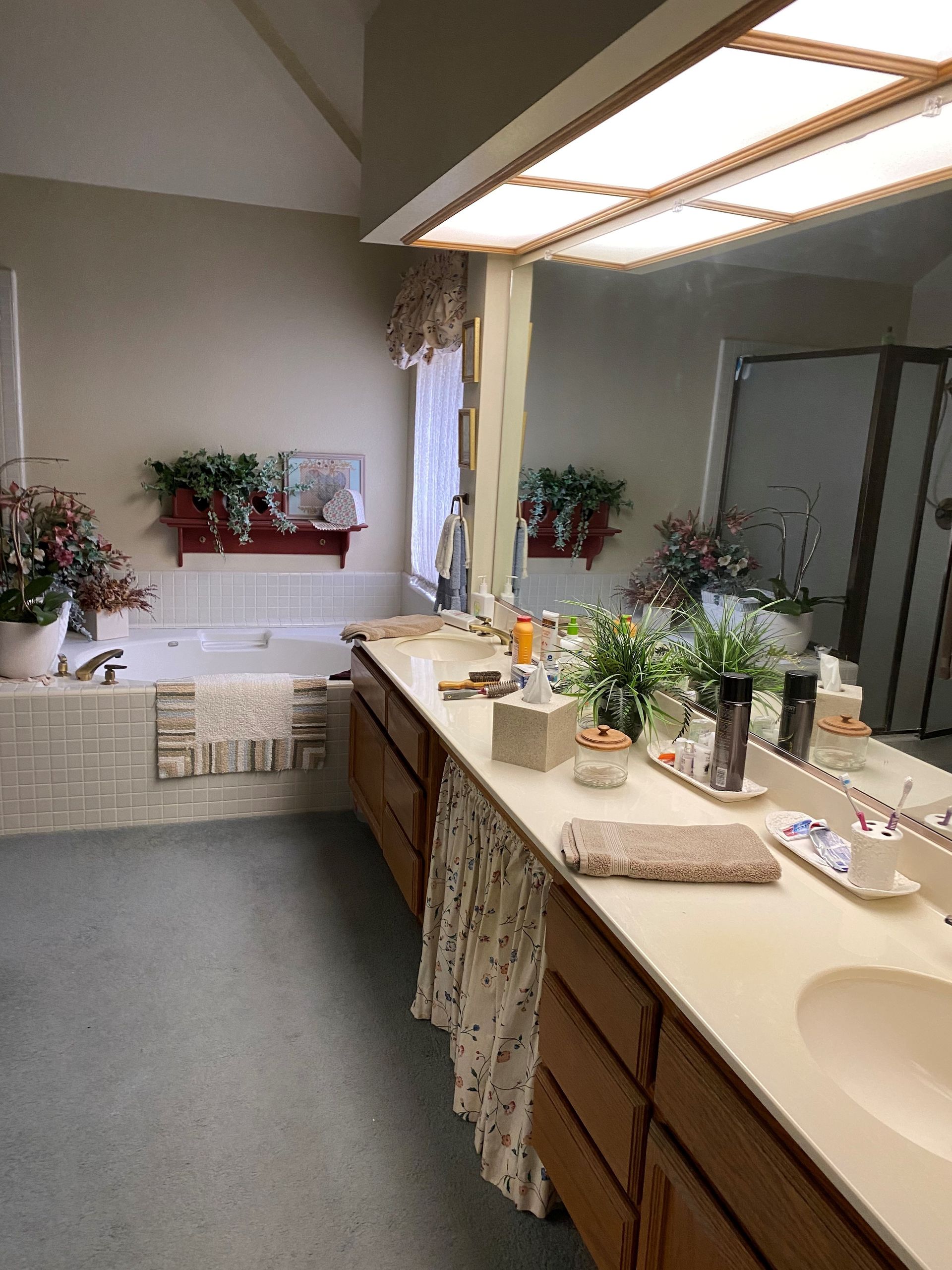 Bathroom vanity with sinks, mirror, and potted plants in a bright, tiled interior.
