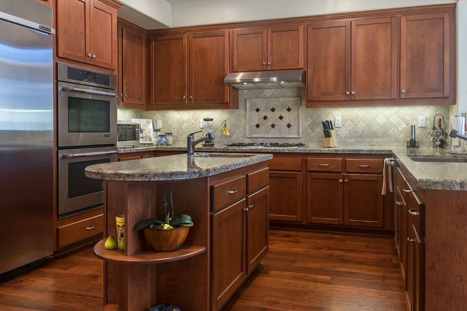 Modern kitchen with dark wood cabinets, stainless appliances, and a central island with a sink