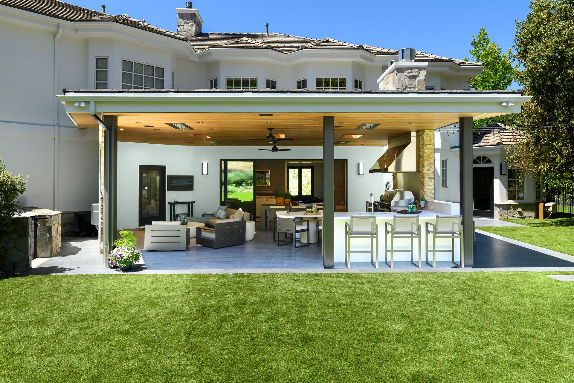 Bright modern kitchen with wood beams, white cabinets, and a large island with flowers.