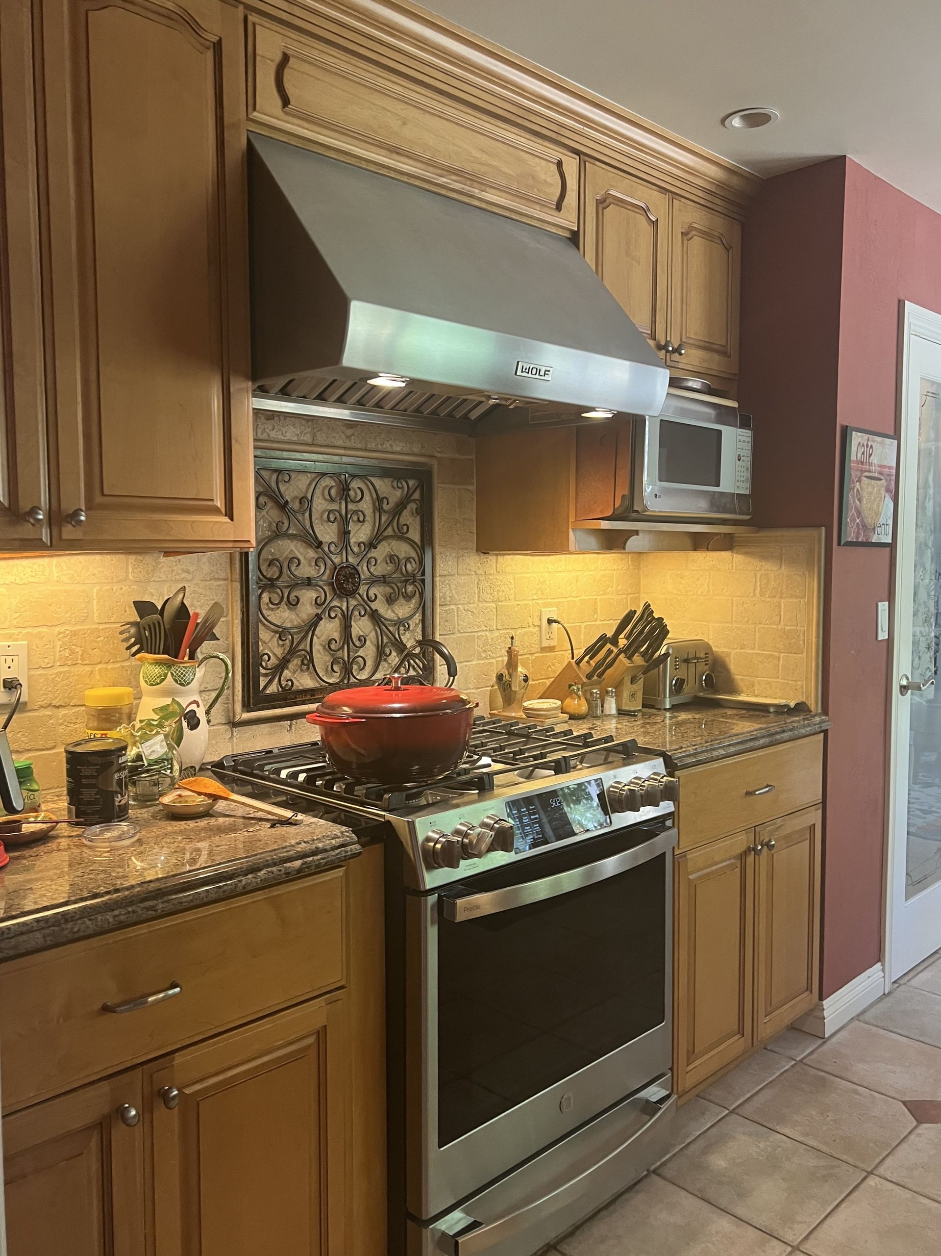 Kitchen with granite island, sink under window, and stainless steel refrigerator in a warm-toned home interior.