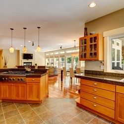 Spacious modern kitchen with wood cabinets, granite counters, tile floor, and bright dining area.