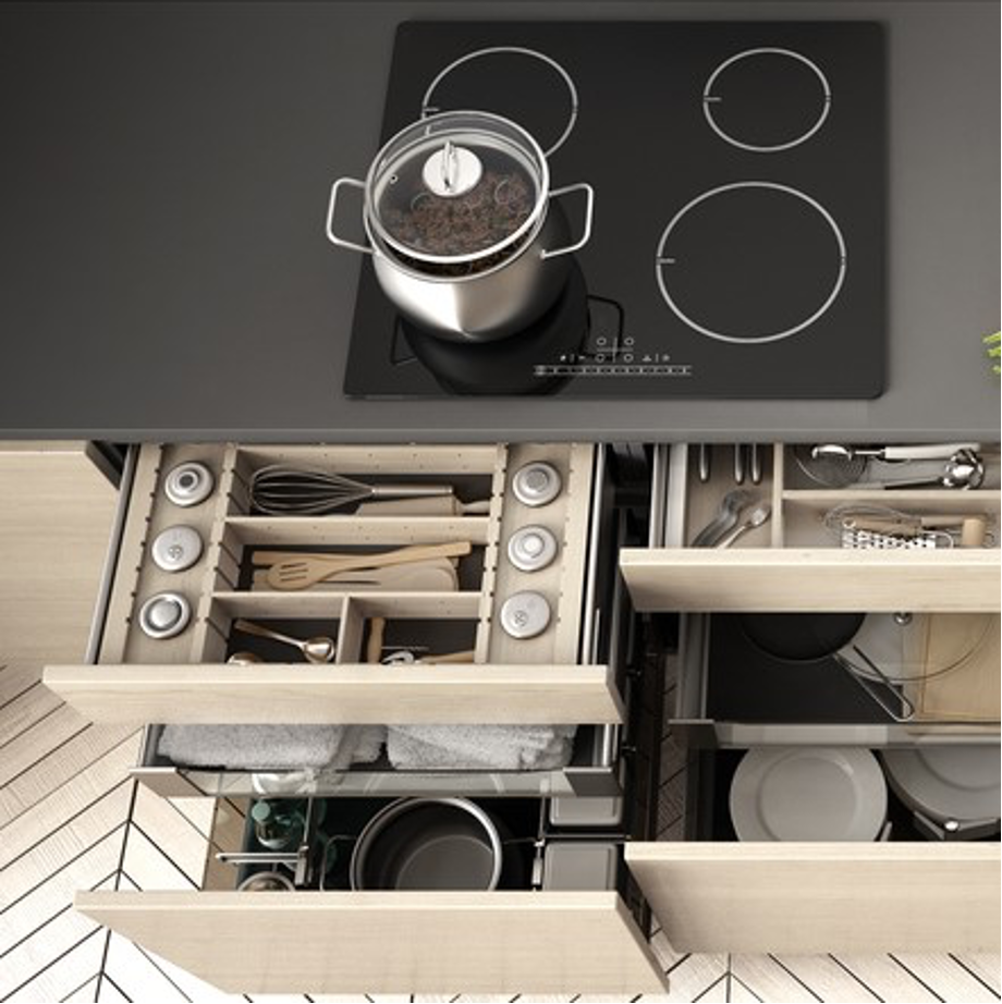Open kitchen drawer with utensils and cookware beneath a black stovetop with a pot on it