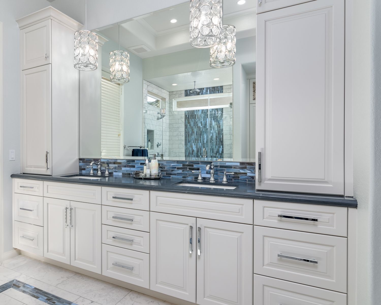 Bright white bathroom vanity with double sinks, mirrors, chrome fixtures, and blue-gray countertop.