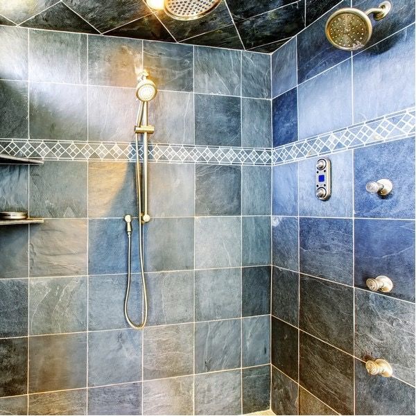 Blue tiled shower with handheld showerhead, multiple wall jets, and built-in shelf.