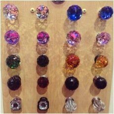 Colorful faceted gemstones arranged in four vertical rows on a tan background