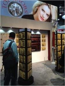 Person walking into a brightly lit storefront display with a large model’s face overhead
