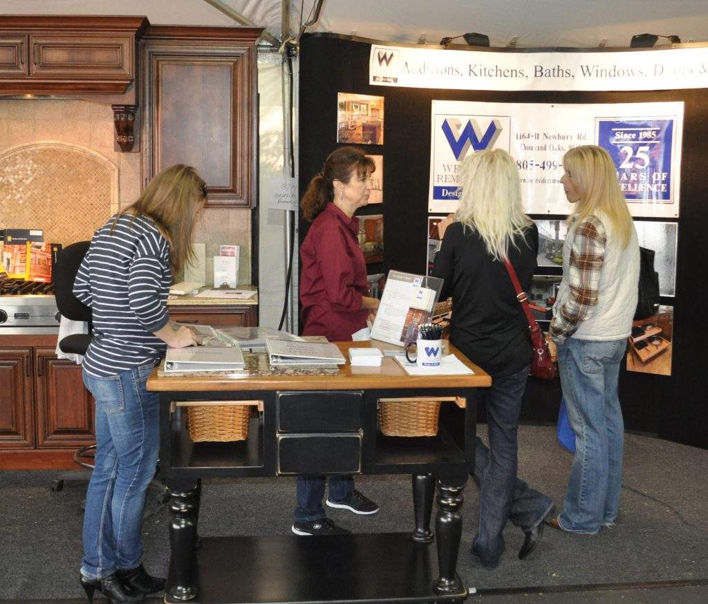 People browsing brochures at a reception desk in a lobby with a sign and display board.