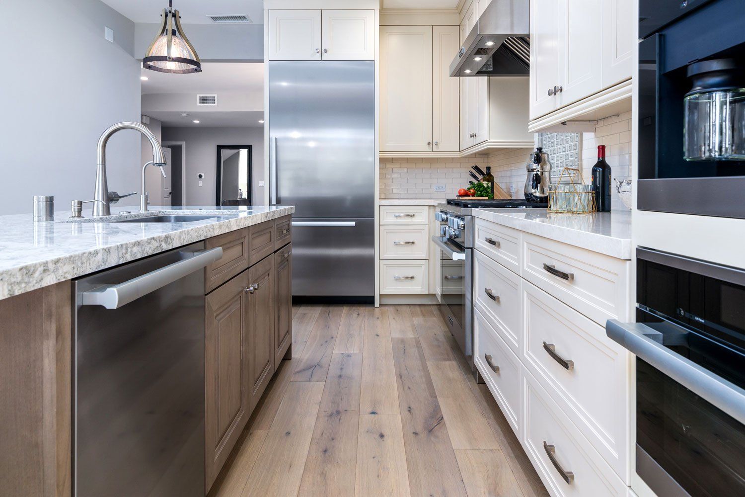 Modern kitchen with white cabinets, stainless appliances, and a large island with dark wood finish