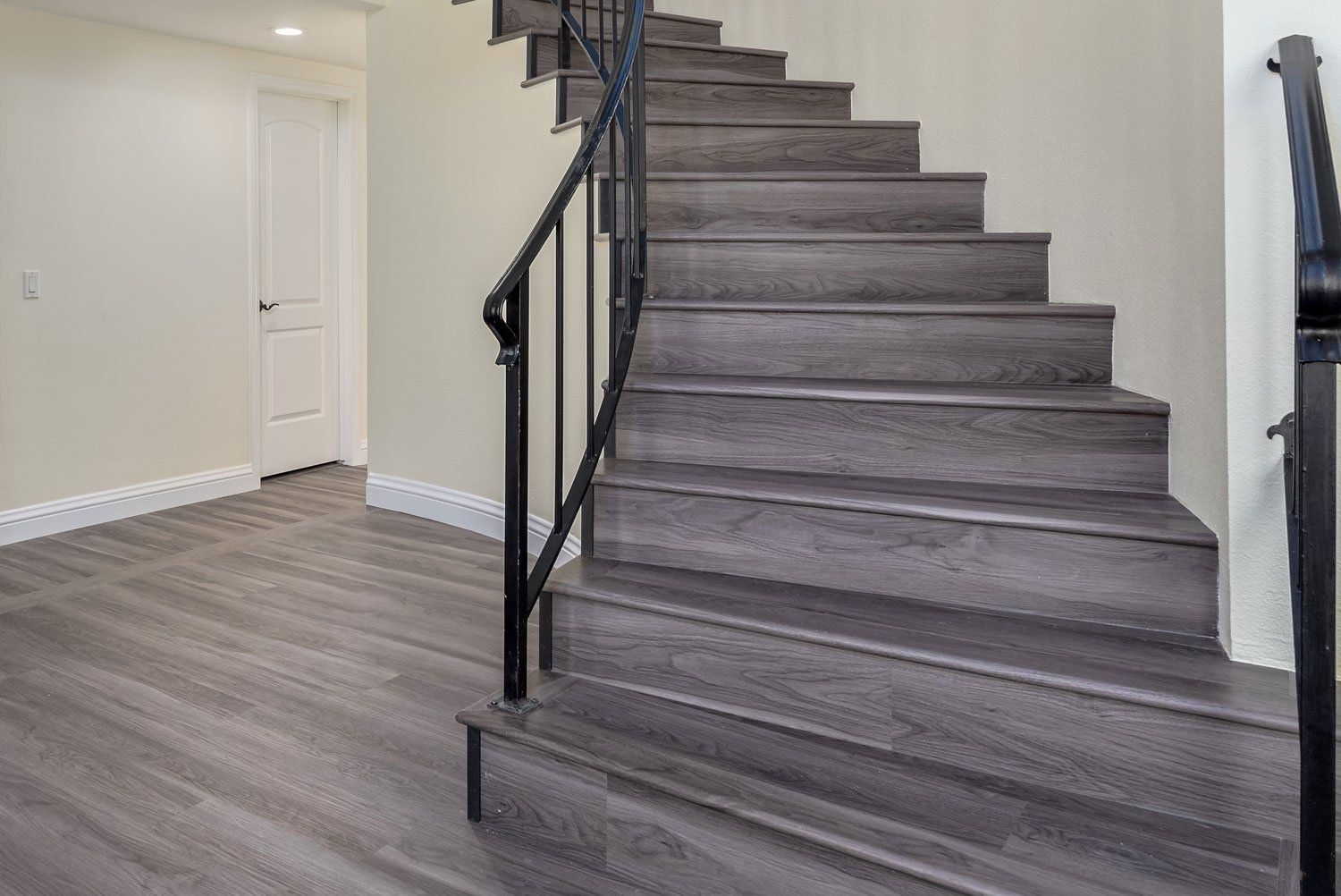 Empty interior with gray wood stairs, black railing, and gray flooring.