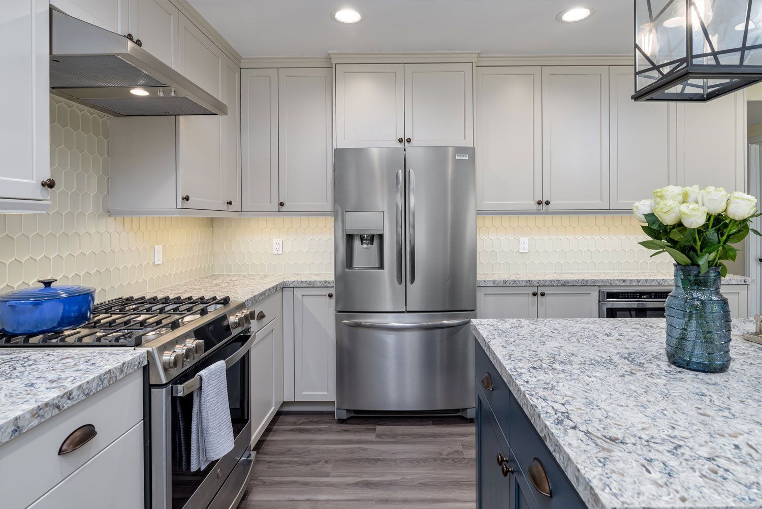 Modern kitchen with stainless steel appliances, gray cabinets, and a granite island with flowers