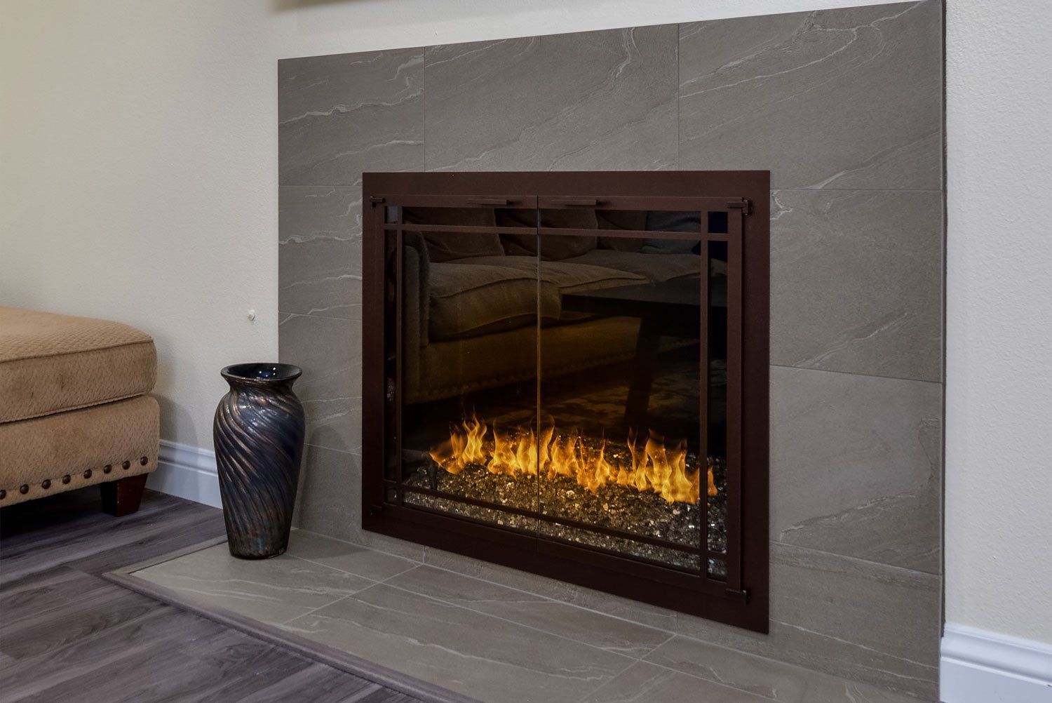 Modern fireplace with glowing flames in a tiled living room, beside a decorative vase.