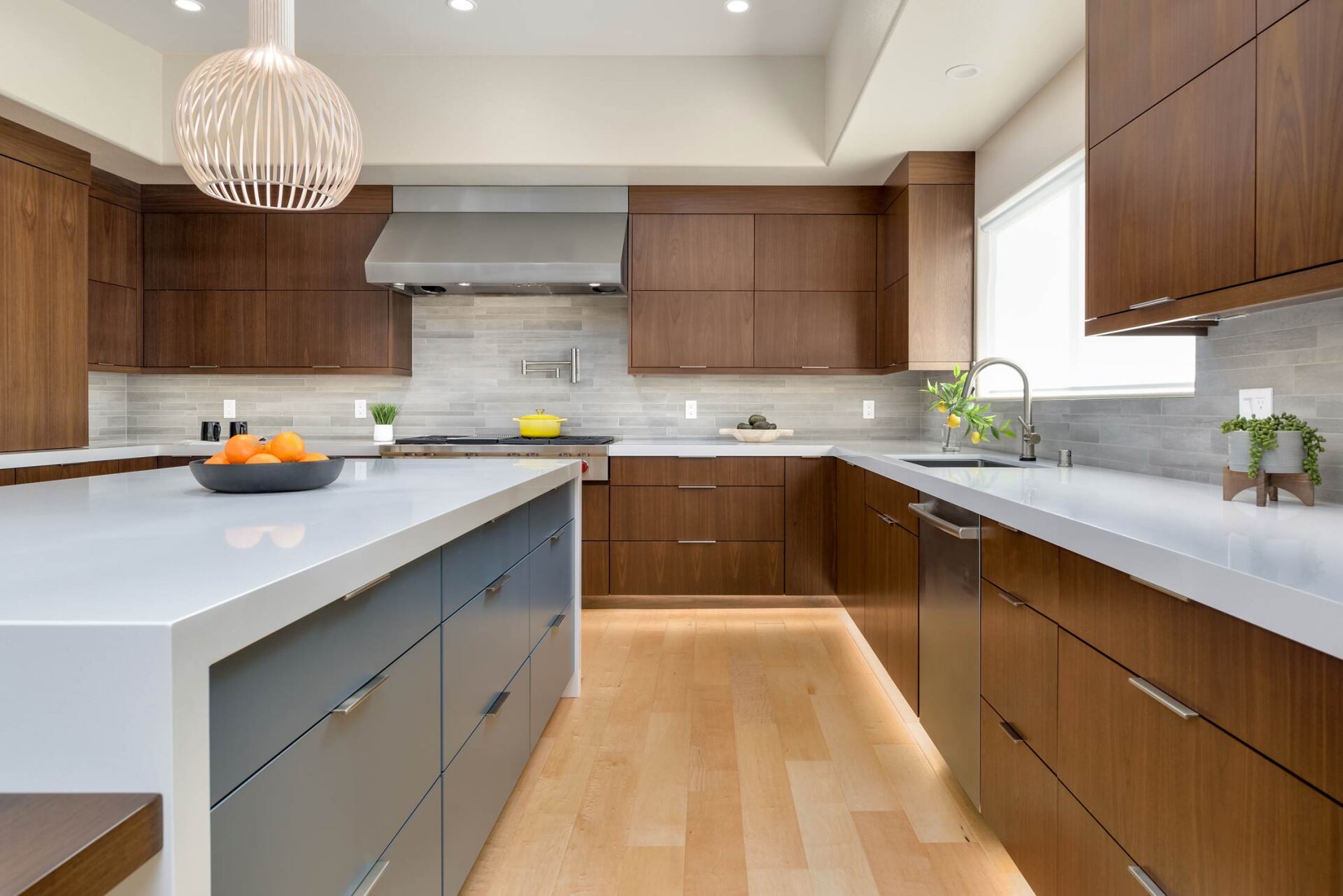 Modern kitchen with white island, wood cabinets, pendant light, and fruit on the counter