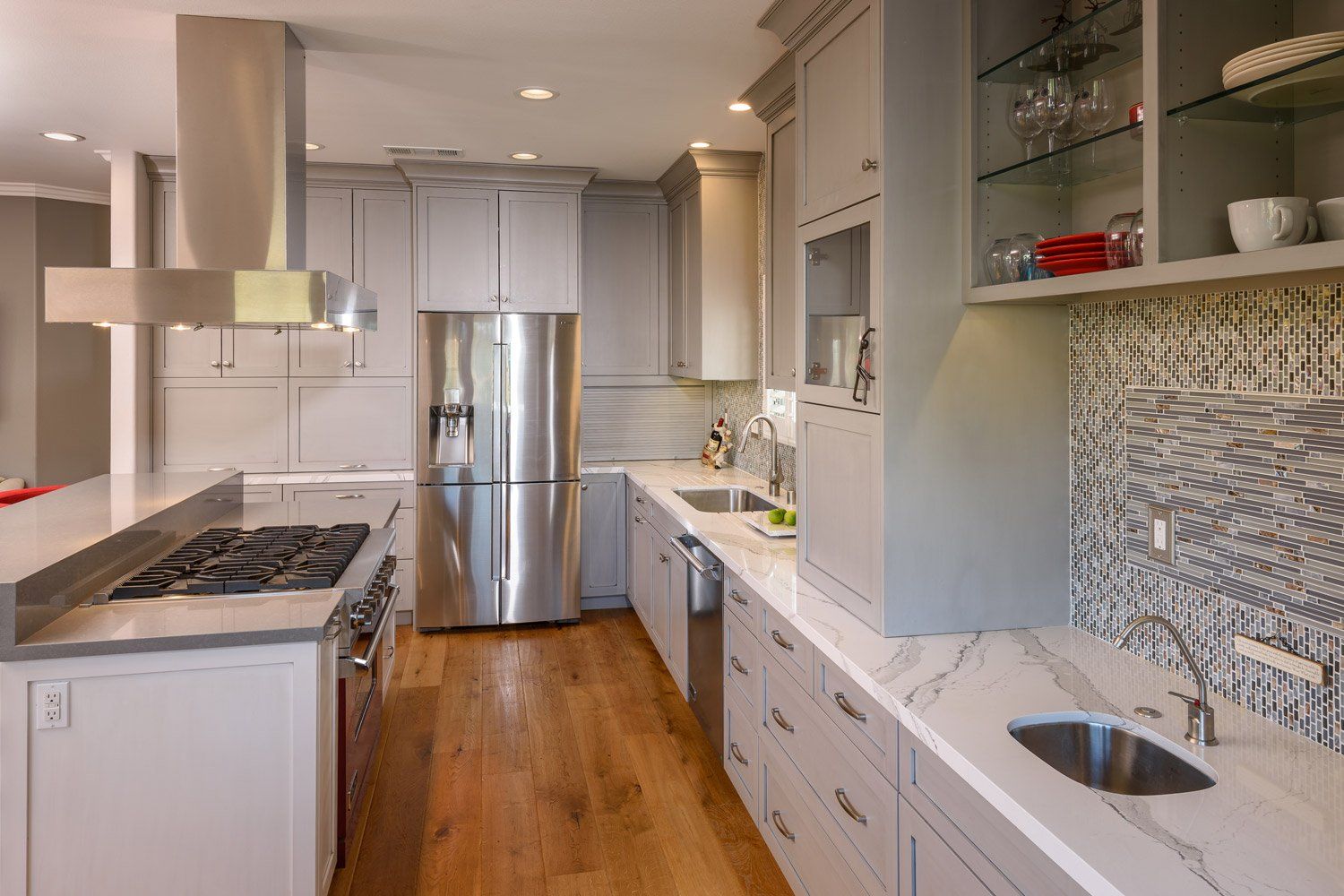 Modern white kitchen with stainless steel appliances, wood floor, and open shelving