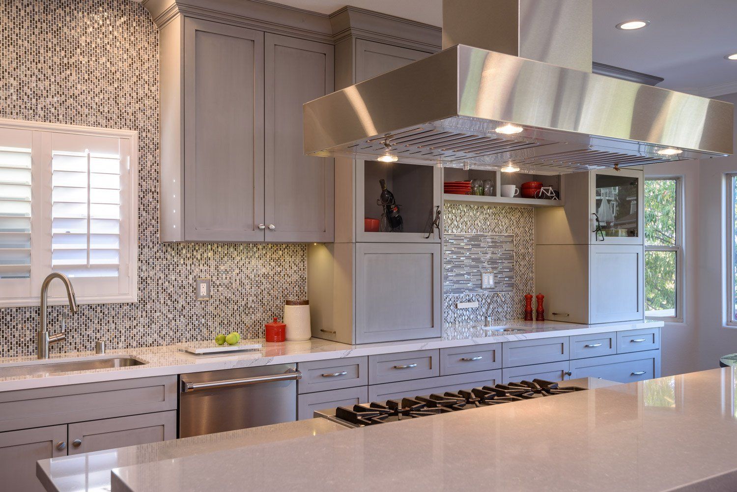 Modern kitchen with white cabinets, mosaic backsplash, and a stainless steel range hood