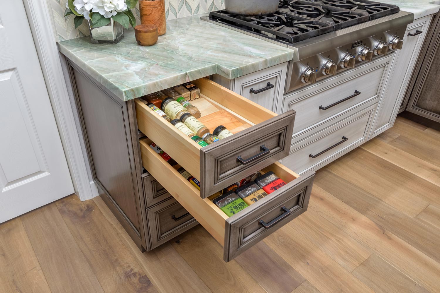 Kitchen island with two open drawers filled with utensils and snacks beside a stove and countertop