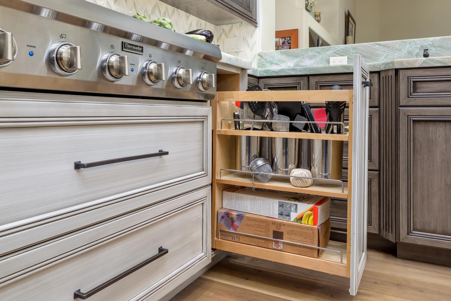 Kitchen island storage cart between stove and cabinet, holding dishes and utensils in a modern kitchen