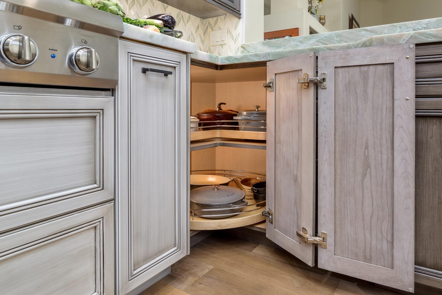 Open kitchen cabinet with shelves holding plates and dishes beside a stove and countertop.