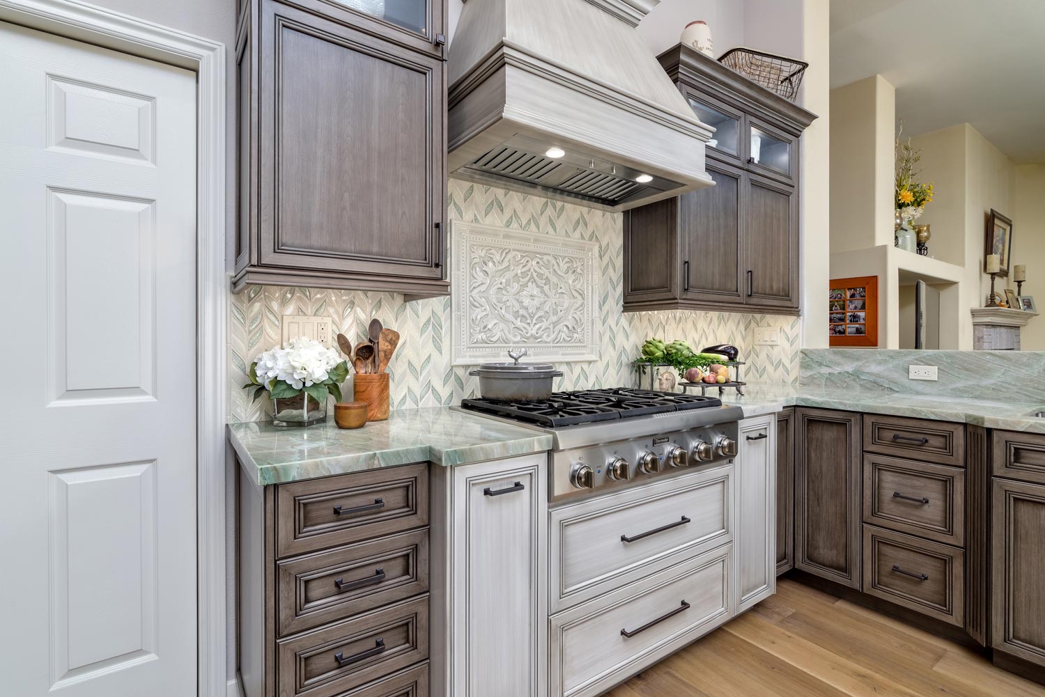 Modern kitchen with white stove, ornate hood, dark wood cabinets, and light marble countertops