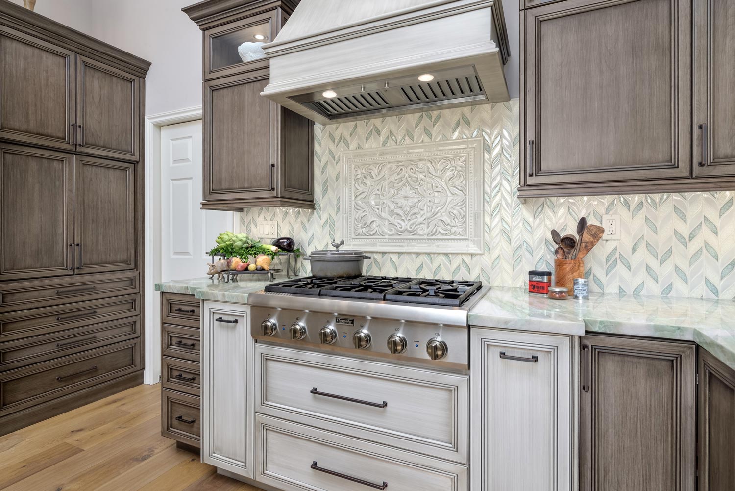 Elegant kitchen with a white range, ornate hood, gray cabinets, and marble backsplash