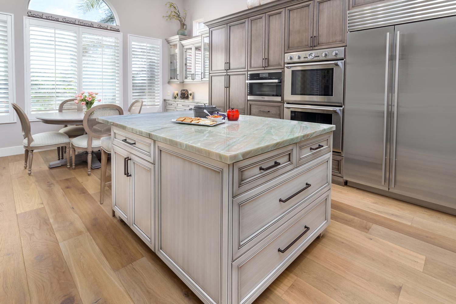 Bright modern kitchen with white cabinets, large island, stainless steel appliances, and dining nook by the windows