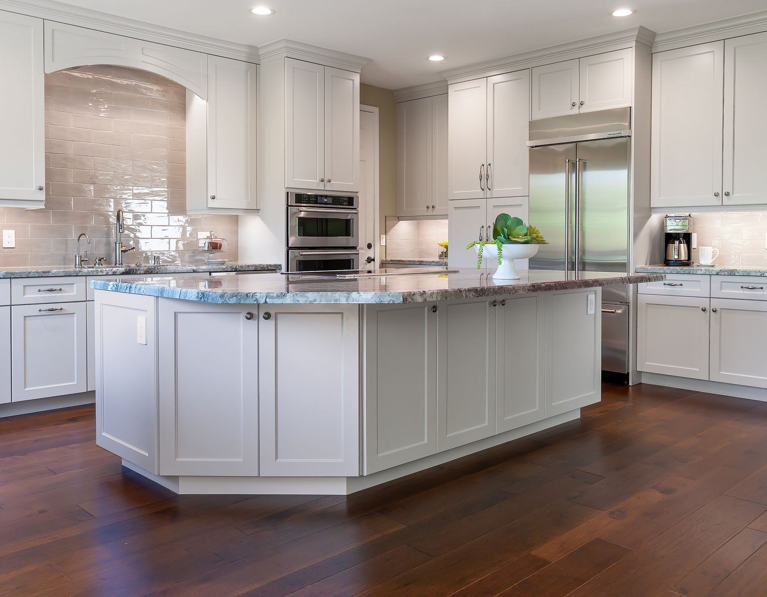 Bright modern kitchen with white cabinets, granite island, stainless steel appliances, and hardwood floors