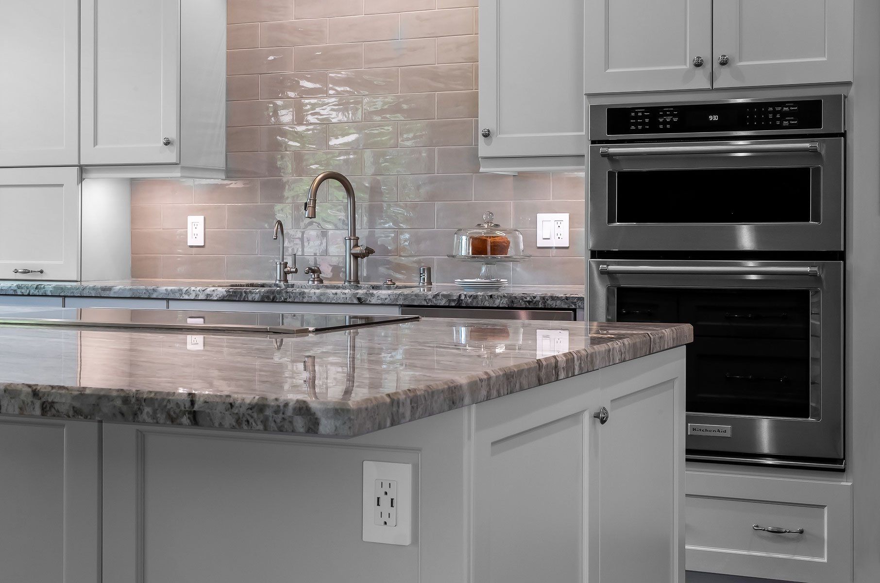 Modern kitchen with granite island, gray cabinets, and built-in double oven